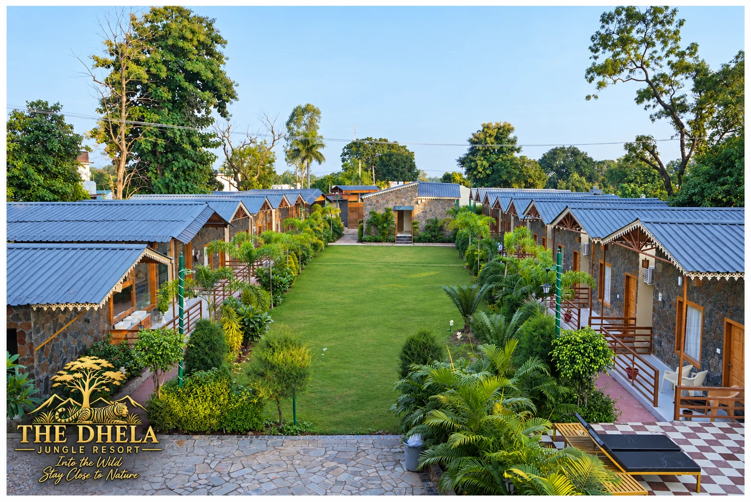 Cottages arranged beside a long central lawn at The Dhela Jungle Resort.