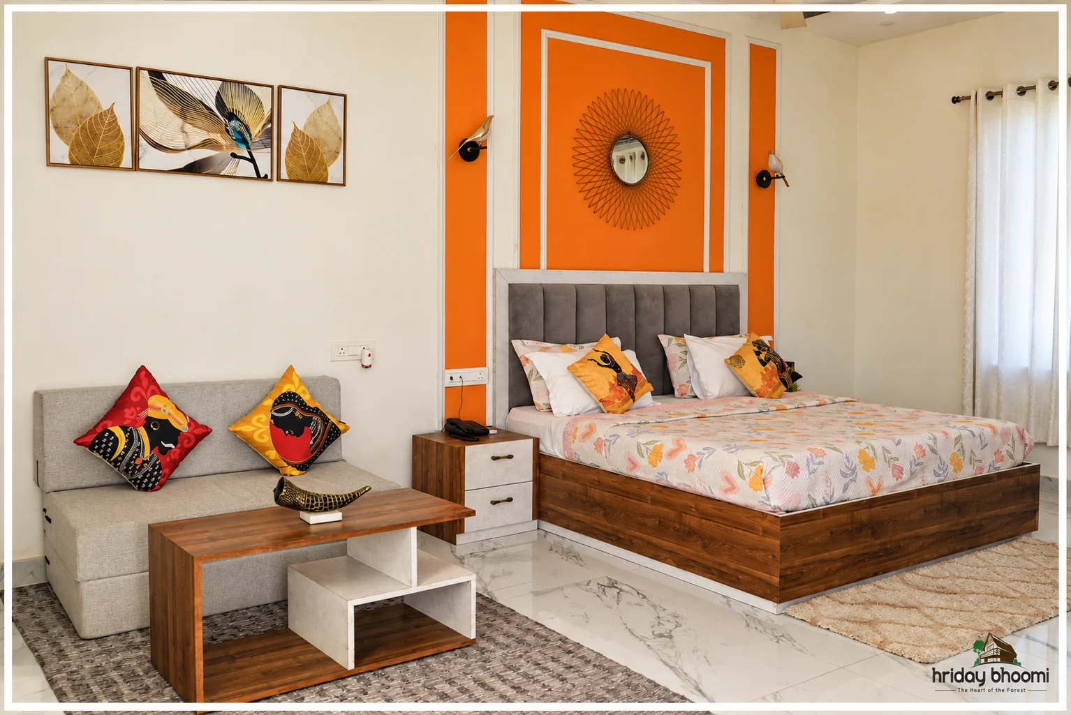 A bright bedroom with orange detailing and a seating area at Hriday Bhoomi.