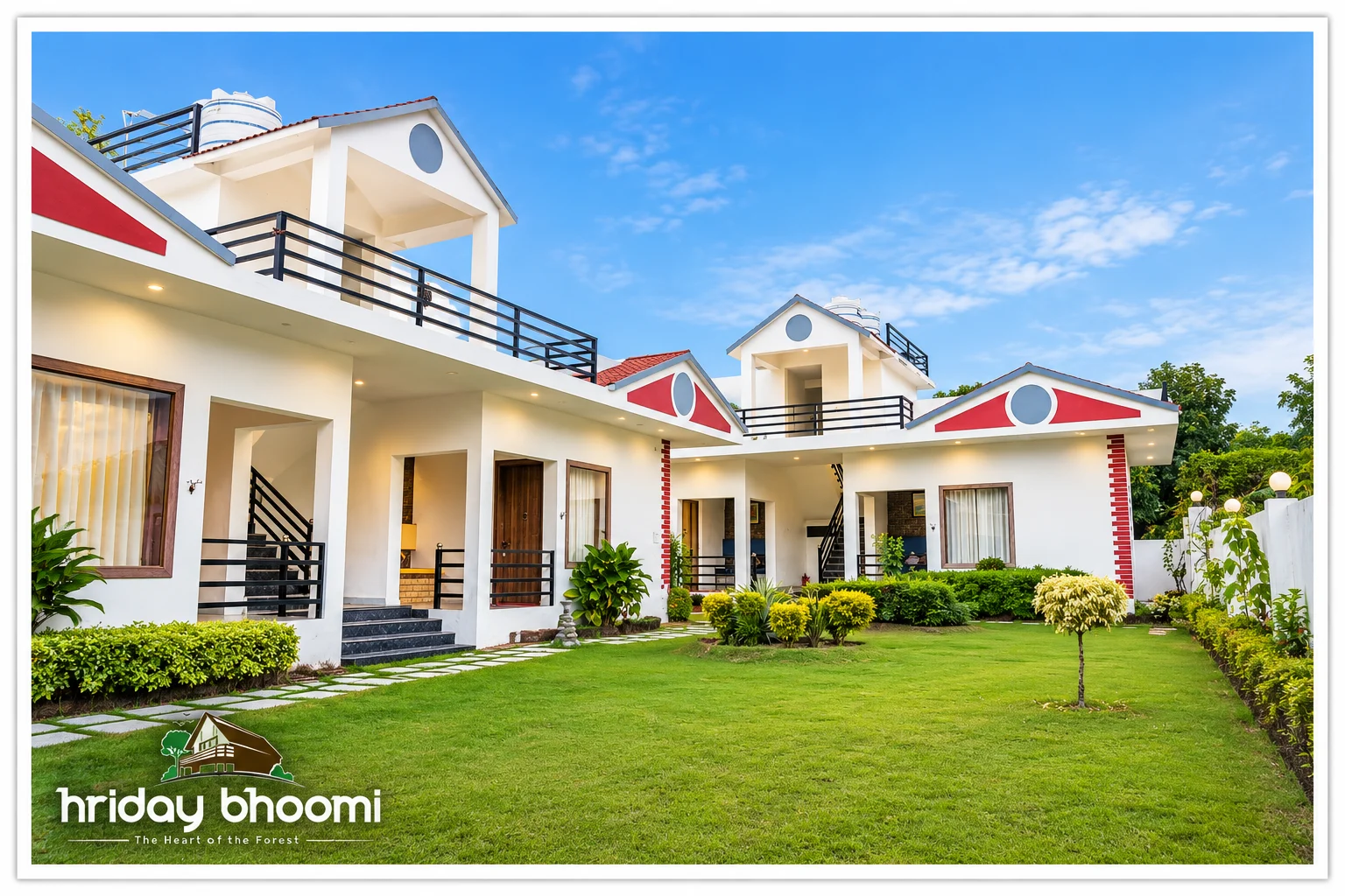 White cottages around a green lawn at Hriday Bhoomi.
